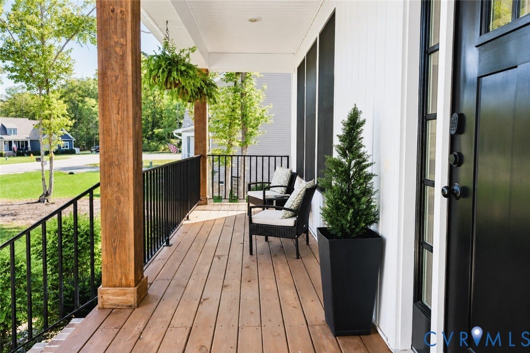 6265 Bushnell Drive, Rochambeau Estates, New Kent, VA 23124 Expansive front porch featuring wood-finish decking, substantial wood-finish columns, black wrought iron railings, and a prominent black entry door with sidelights