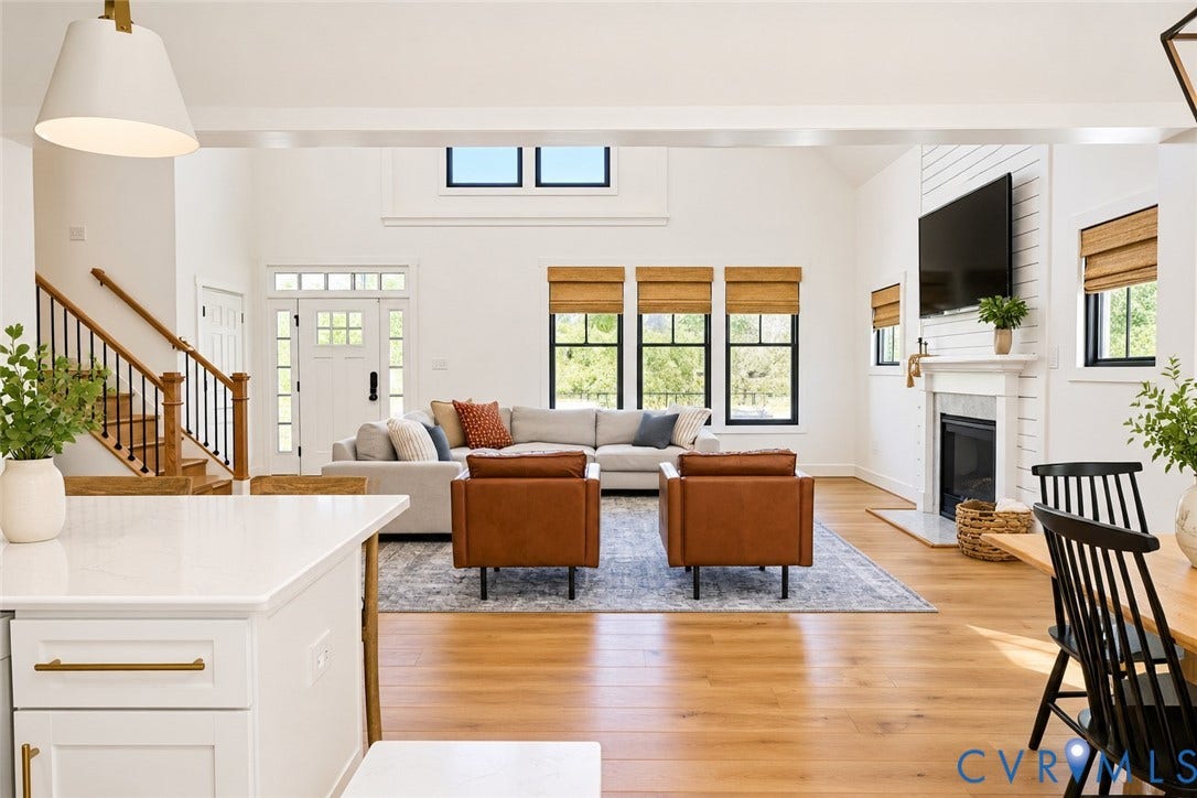 6265 Bushnell Drive, Rochambeau Estates, New Kent, VA 23124 Vaulted ceilings, wood-finish flooring, staircase with dark metal balusters, fireplace with mantel, and white shaker cabinetry with brass hardware