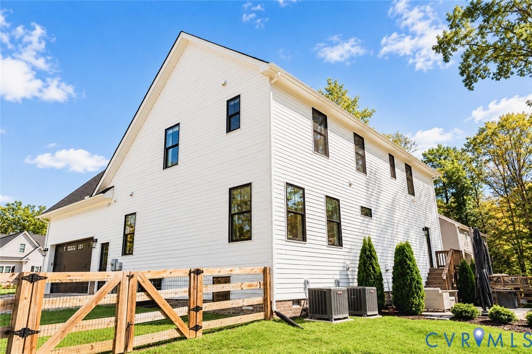 6265 Bushnell Drive, Rochambeau Estates, New Kent, VA 23124 White siding exterior with multiple dark-framed windows, a pitched roof, and a two-car garage with a dark door
