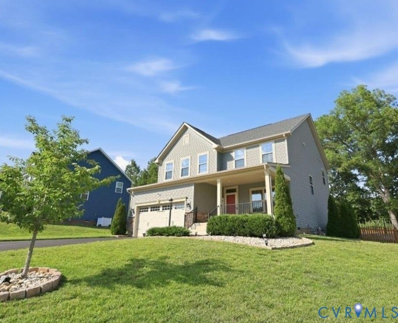 Two-story residence with a covered front porch, attached garage, and light-toned siding