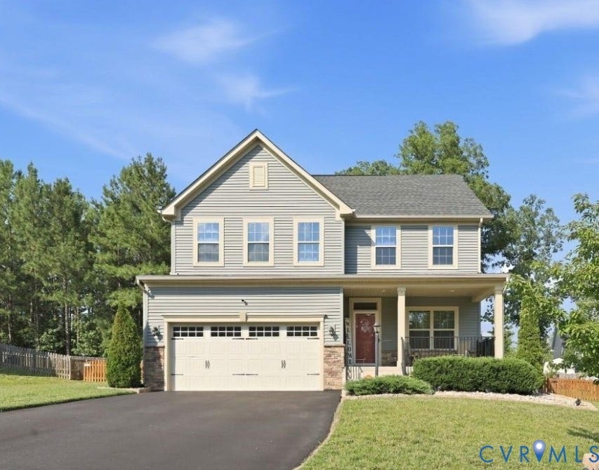 Two-story residence featuring light gray siding, an integrated two-car garage, and a covered front porch with columns