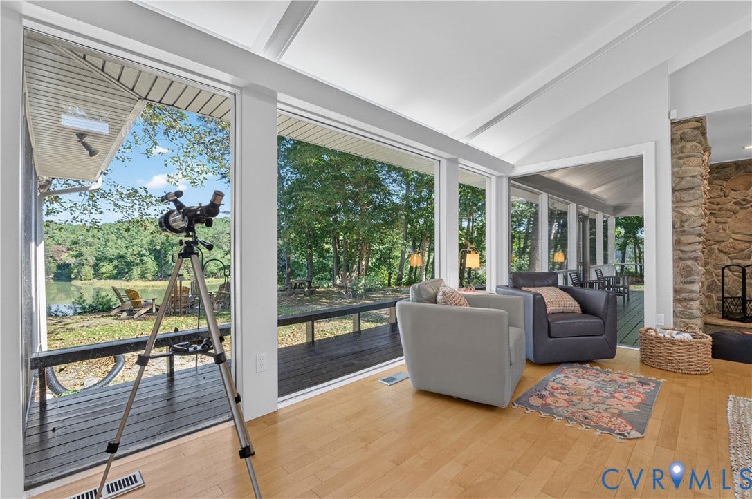 Vaulted ceiling, wood-finish flooring, stone-clad fireplace, large windows, and a screened-in porch