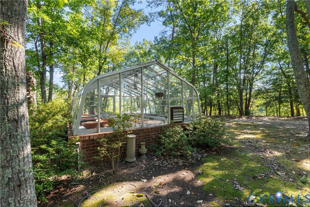 Greenhouse structure featuring a brick base, clear paneling, and integrated ventilation