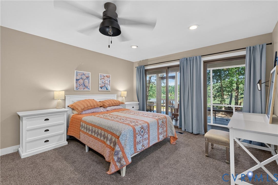 Recessed ceiling lighting, ceiling fan, sliding glass doors, carpet flooring, and a white paneled headboard