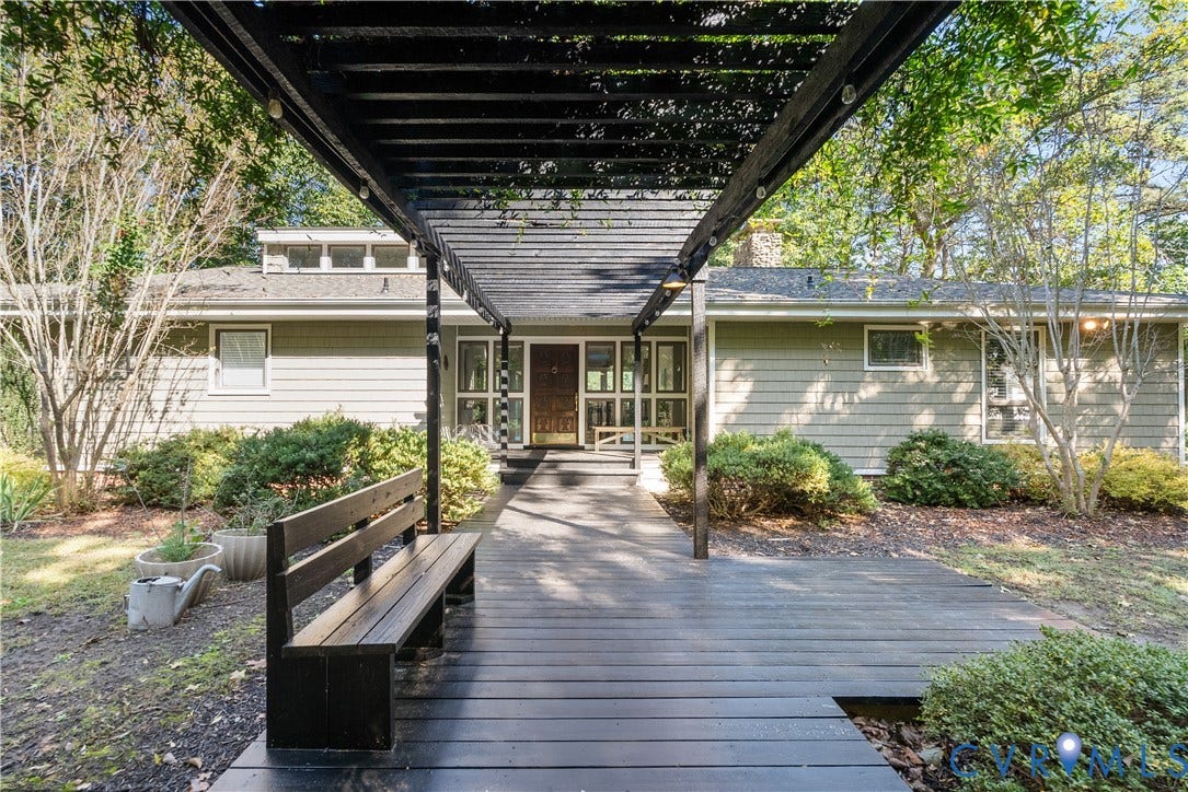 Expansive front walkway with a dark wood-finish deck and integrated bench