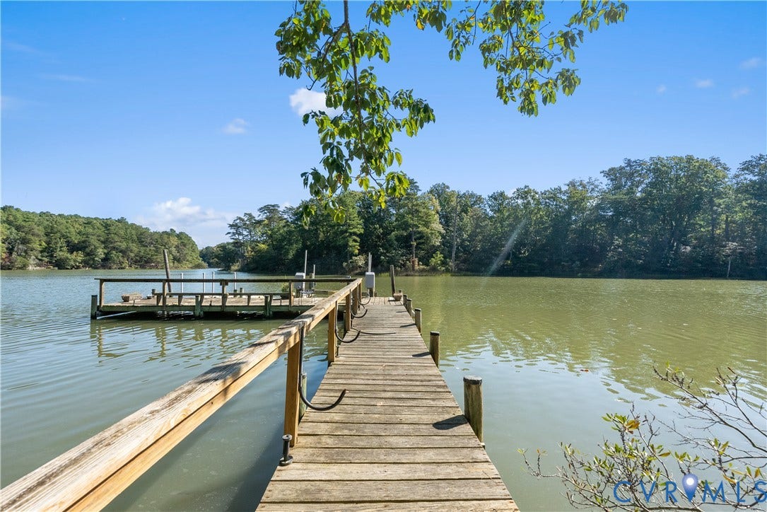 Wood-plank dock with a handrail, leading to a boat lift and an additional dock platform