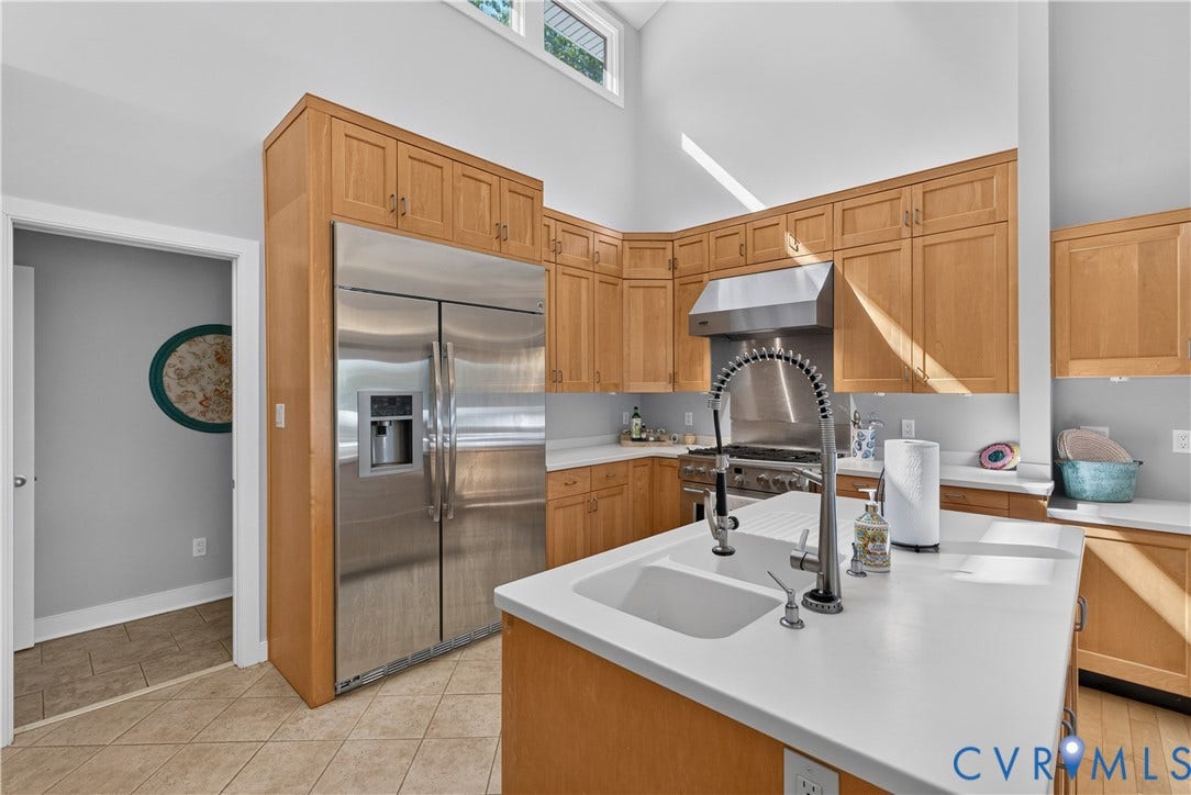 High vaulted ceilings with clerestory windows, stainless steel appliances, extensive wood cabinetry, white countertops, and a kitchen island with a built-in sink