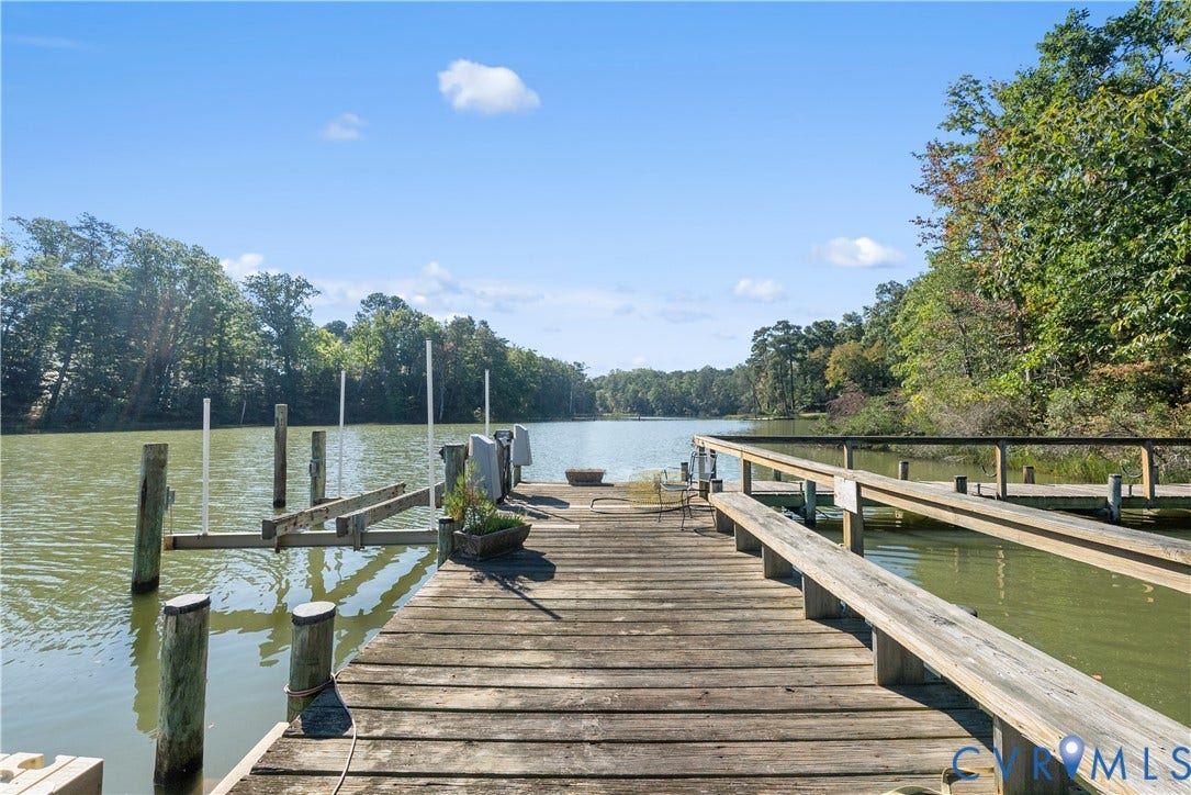 Waterfront property featuring a wooden dock, boat lift, and perimeter seating