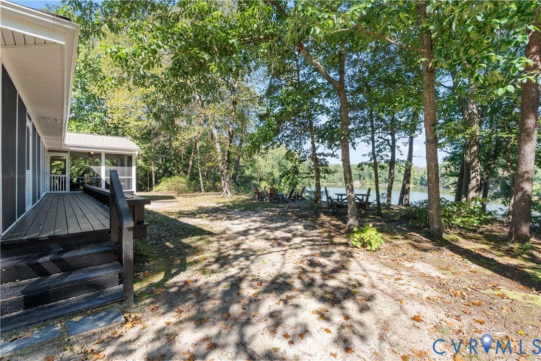 Spacious outdoor deck with steps, screened-in porch, mature trees, and waterfront access