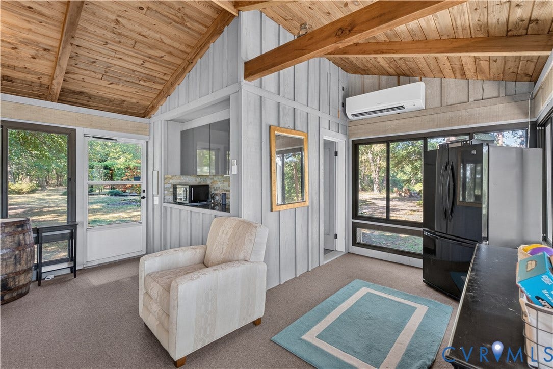 Vaulted wood-plank ceiling with exposed beams, wood-finish wall paneling, built-in cabinetry, and black-framed windows
