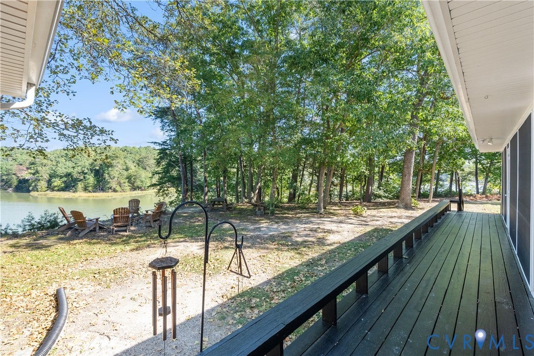 Expansive outdoor deck with a dark finish, offering waterfront access and surrounded by mature trees