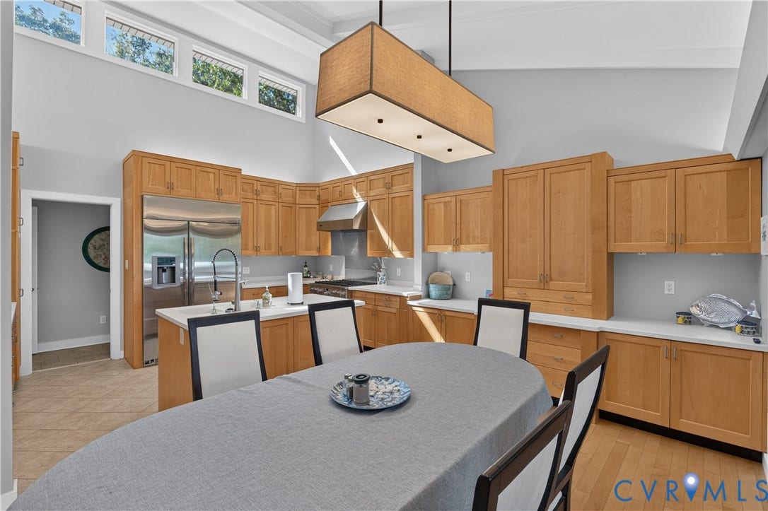 Kitchen featuring vaulted ceilings, clerestory windows, wood cabinetry, stainless steel appliances, and a central island with a sink