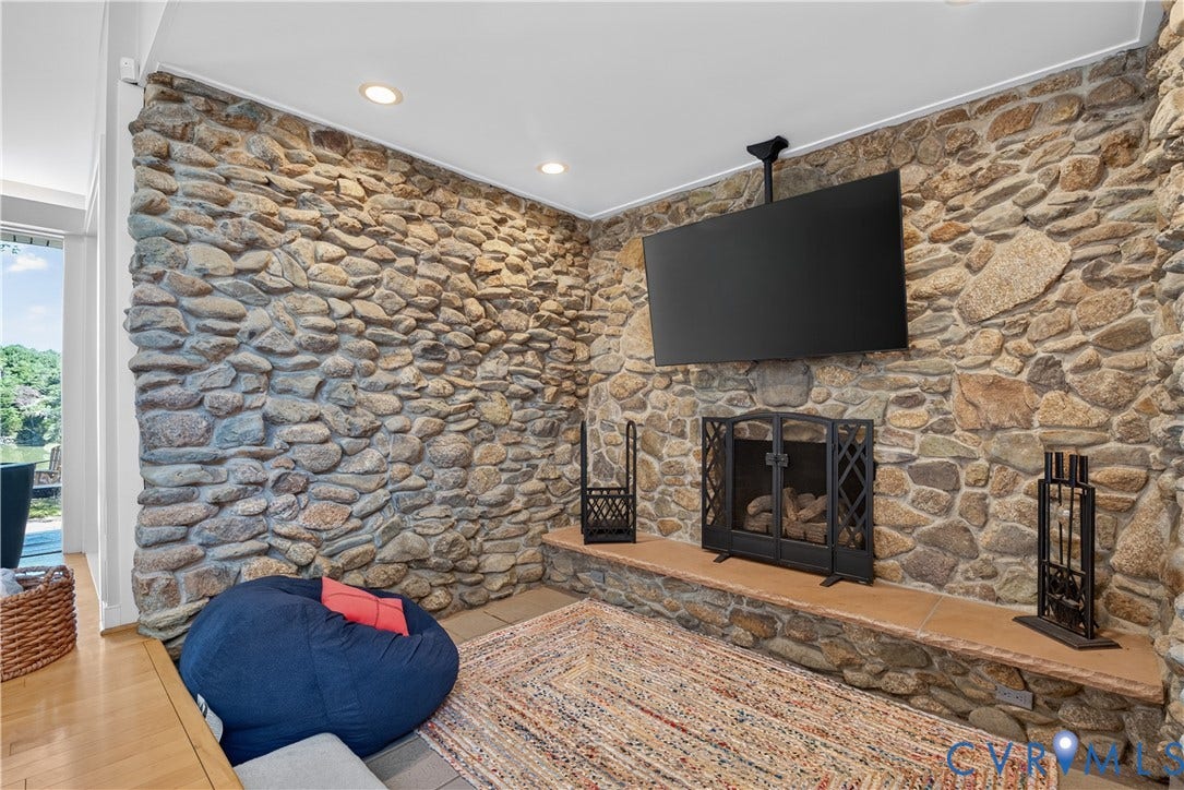 Stone accent wall with built-in fireplace, hearth, and recessed lighting