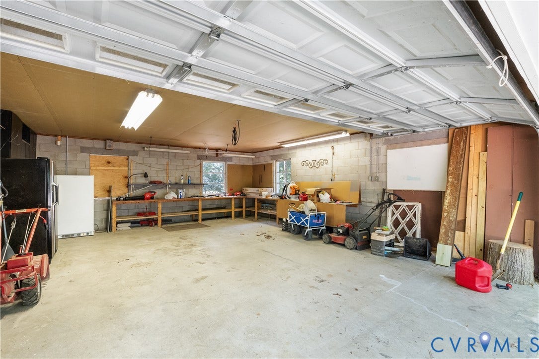 Concrete flooring, block wall construction, built-in shelving, overhead fluorescent lighting, and a paneled garage door