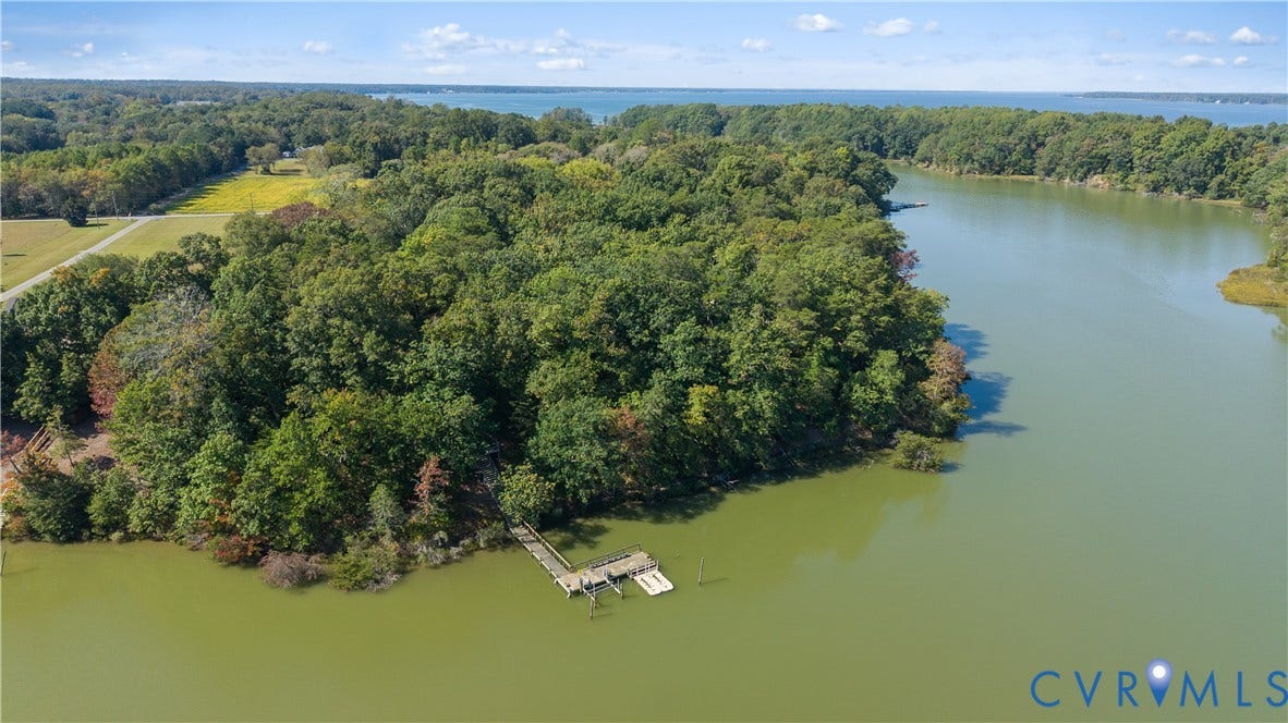 Waterfront property featuring a wooded shoreline, private dock, and open water access