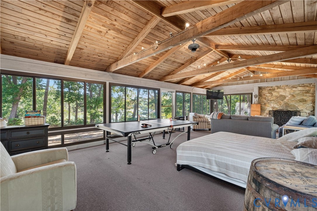 Vaulted wood plank ceiling with exposed beams, stone accent wall, recessed lighting, and wall of windows