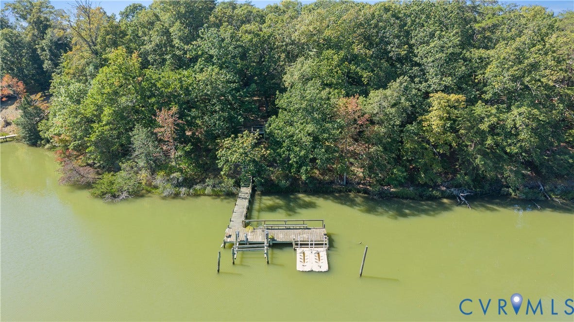 Waterfront property featuring a private dock, forested shoreline, and clear water access