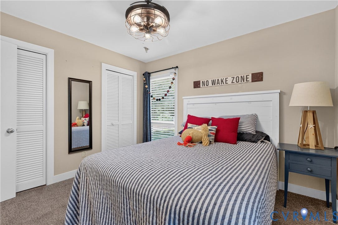 Neutral wall color, carpet flooring, a white paneled headboard, and two louvered closet doors
