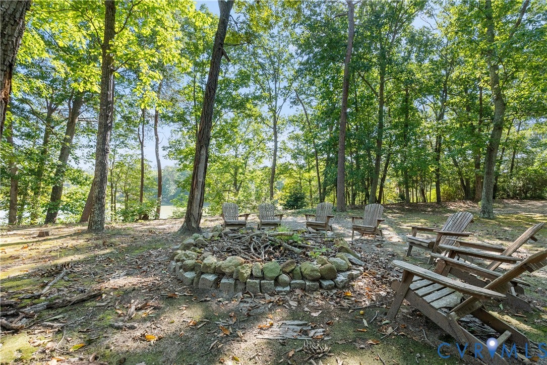 Wooded setting featuring a stone-lined fire pit and mature trees