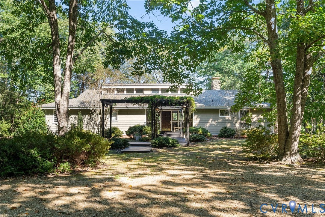 Exterior featuring a covered entry, pergola, stone chimney, and sloped roofline