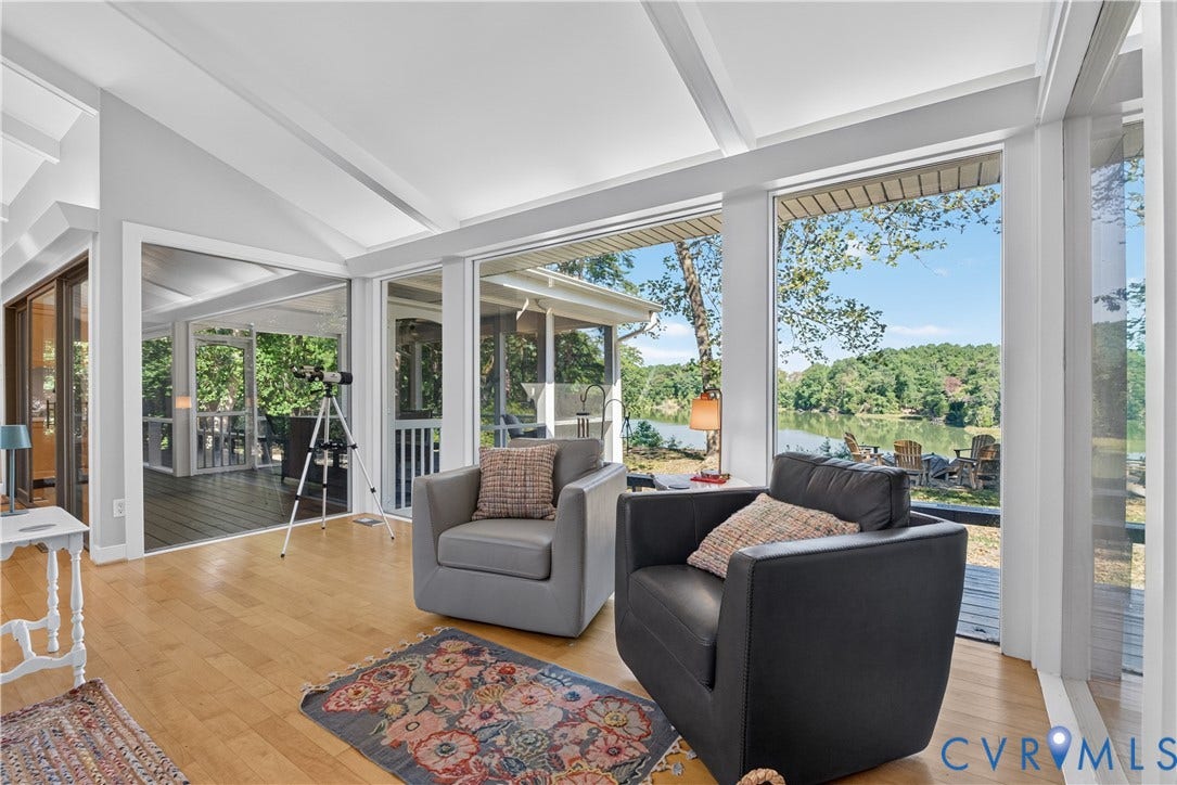 Vaulted ceilings and wood-finish flooring complement the expansive windows and glass sliding doors, leading to a screened porch