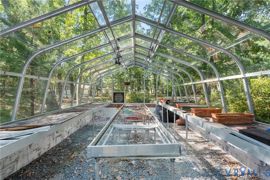 Curved glass-paneled greenhouse structure with metal framing and a gravel floor