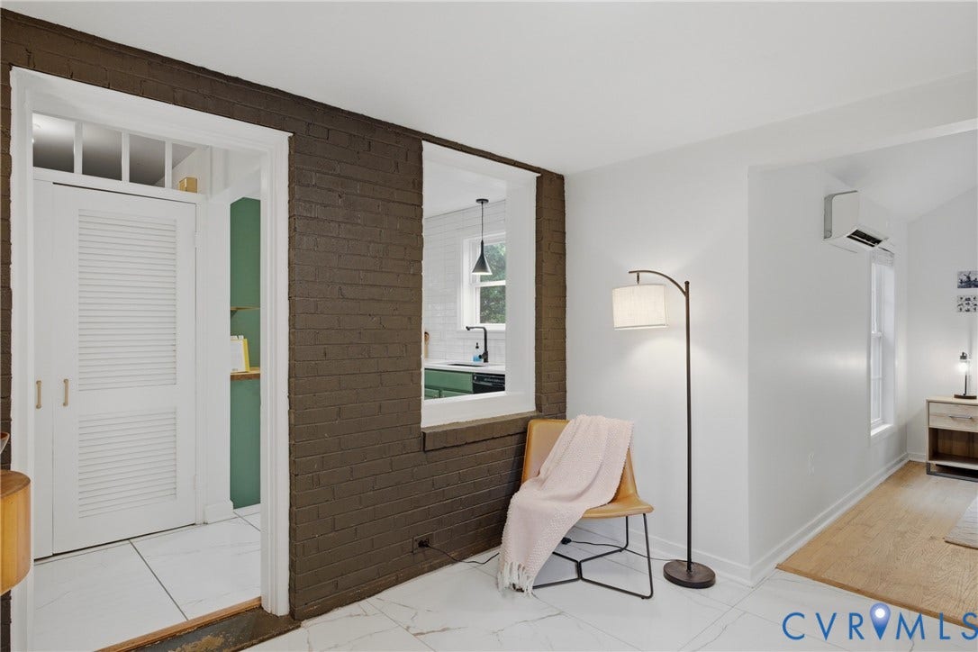 White tile flooring, exposed brick wall, pass-through window,  and minisplit