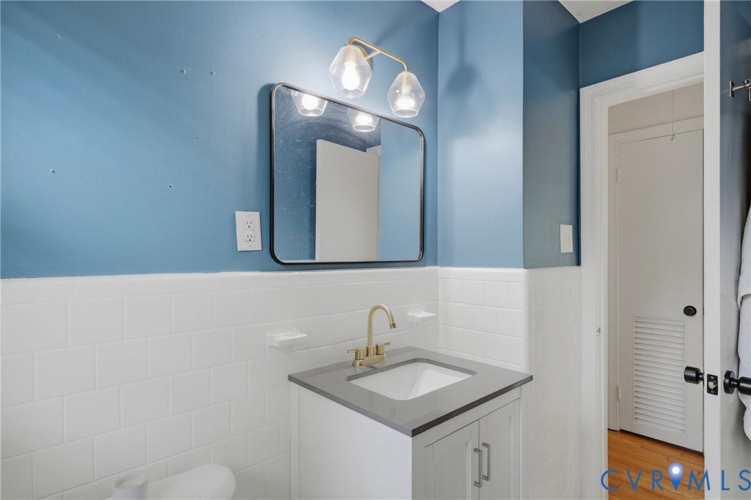 Vanity with an integrated sink, gold-finish faucet, and modern light fixture