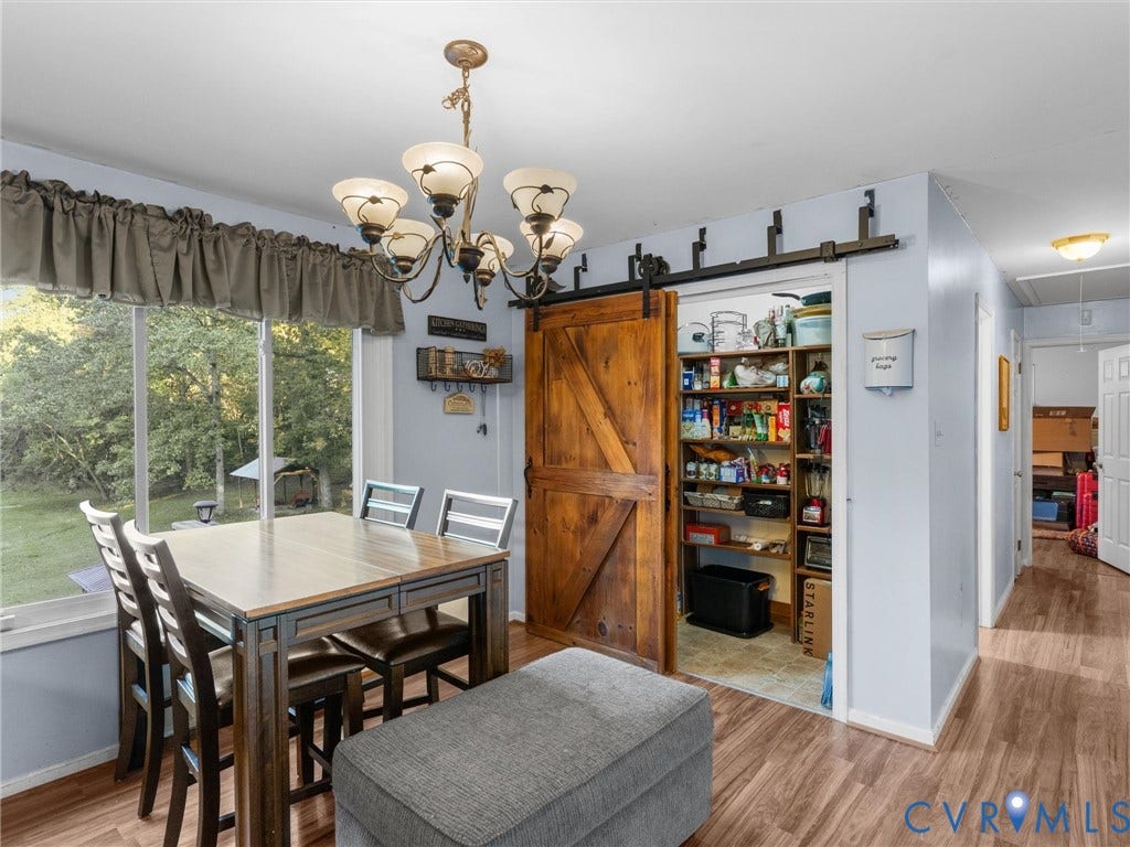8251 Old Roxbury Road, Quinton, VA 23141 Custom wood barn door on a black metal sliding track, wood-finish flooring, multi-tier traditional chandelier, and built-in pantry shelving