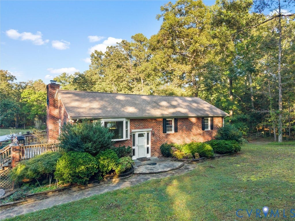 8251 Old Roxbury Road, Quinton, VA 23141 Single-story brick exterior featuring a shingle roof, chimney, expansive wooden deck, and front entryway with a bay window