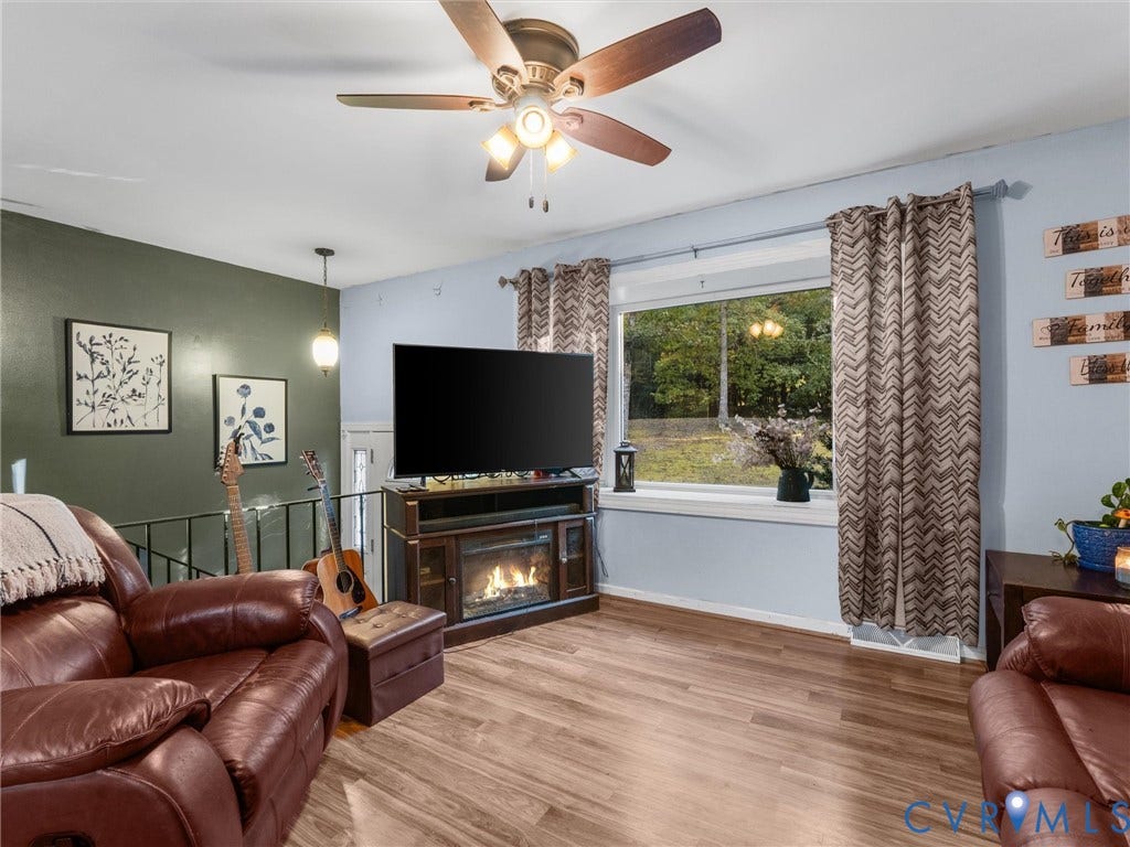 8251 Old Roxbury Road, Quinton, VA 23141 Living area featuring wood-finish flooring, a ceiling fan with integrated lighting, an accent wall, and a large picture window
