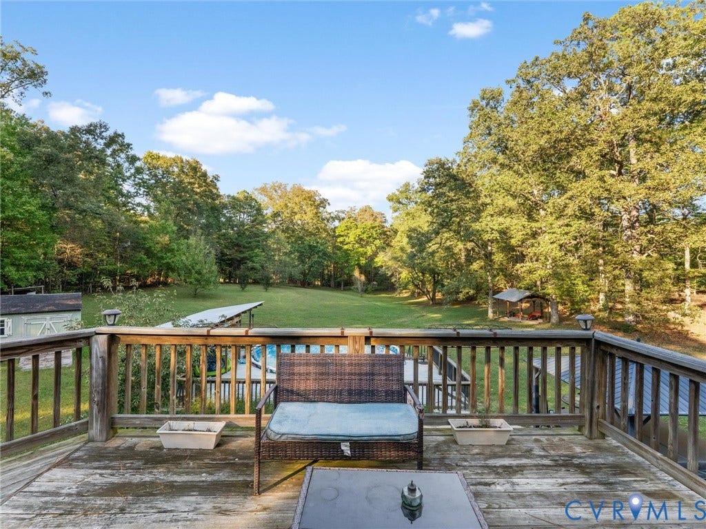 8251 Old Roxbury Road, Quinton, VA 23141 Elevated wooden deck featuring a perimeter railing, overlooking an expansive backyard with mature trees and a detached structure