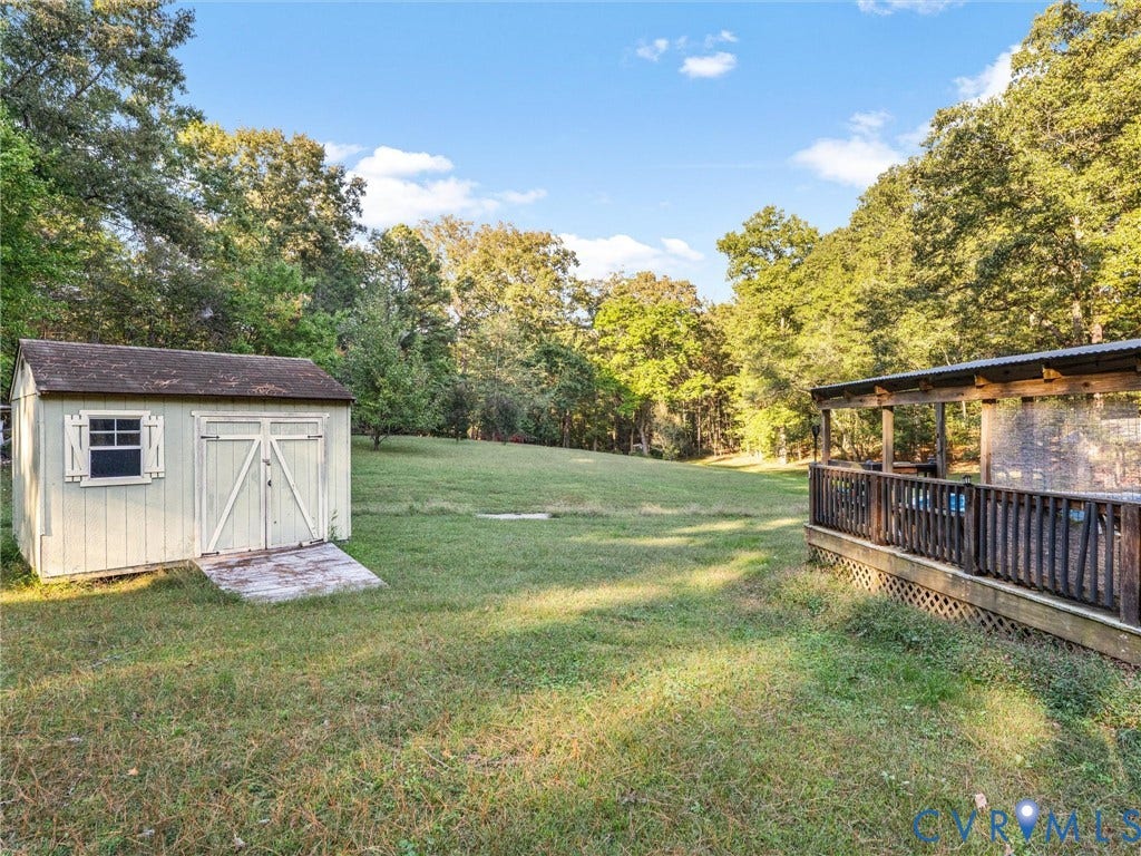 8251 Old Roxbury Road, Quinton, VA 23141 Spacious backyard featuring a detached storage shed, a covered wooden deck with railing, and mature surrounding trees