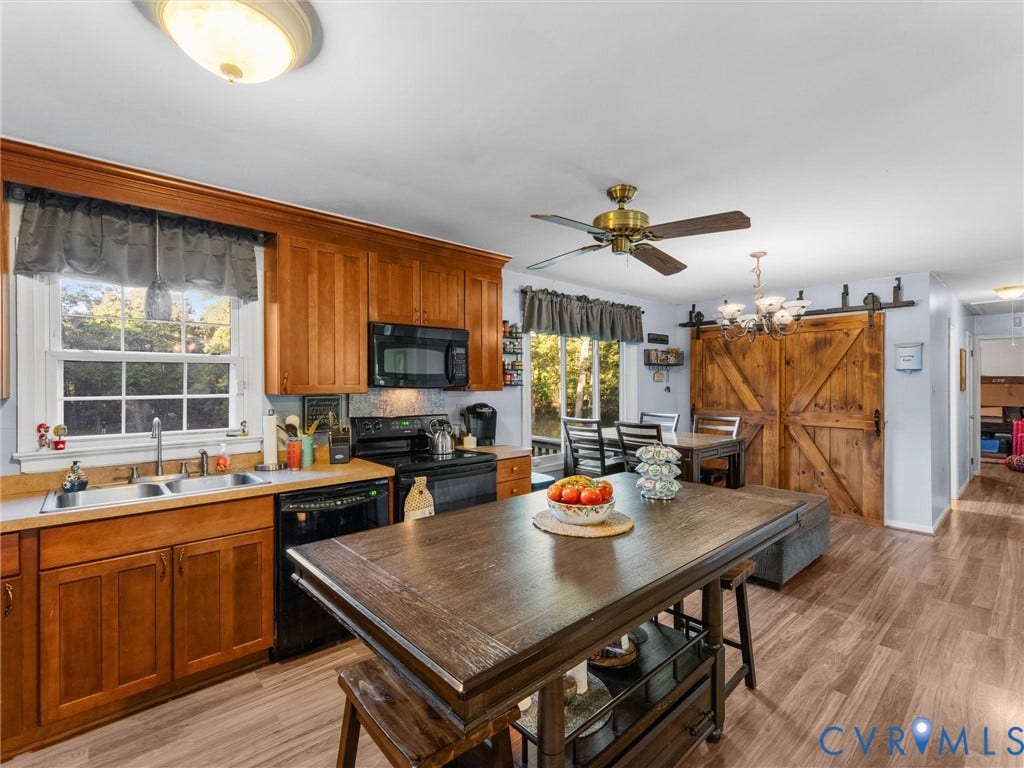 8251 Old Roxbury Road, Quinton, VA 23141 Kitchen featuring wooden cabinetry, dual-basin stainless steel sink, ceiling fan, wood-finish flooring, and sliding wood barn-style doors