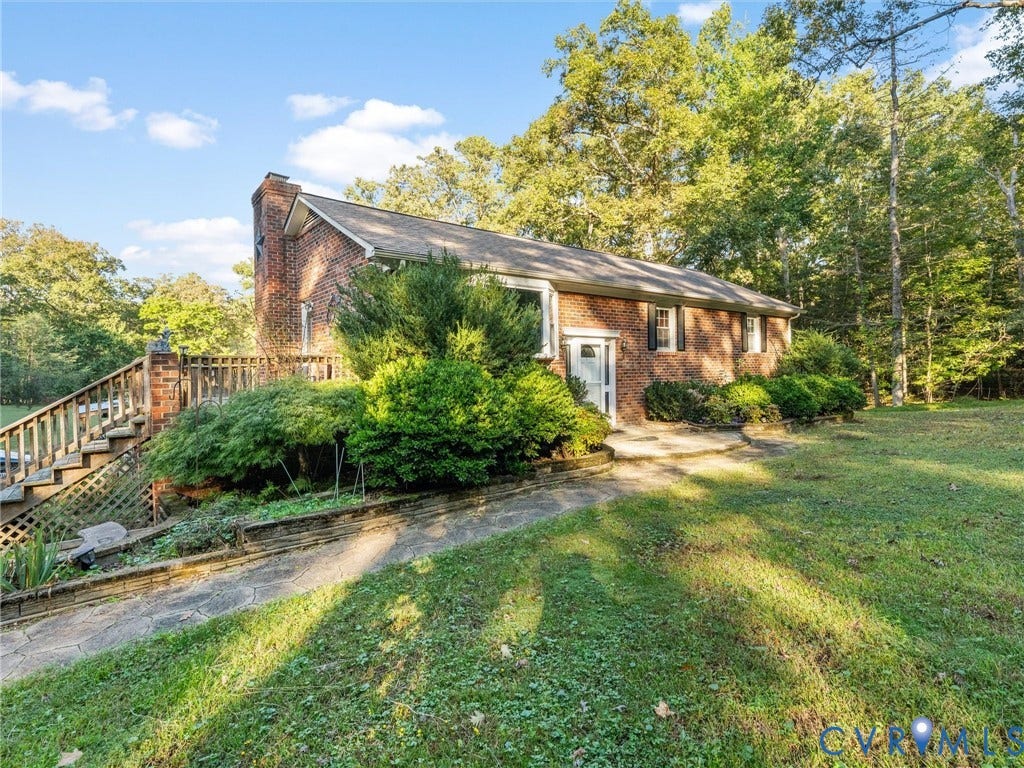 8251 Old Roxbury Road, Quinton, VA 23141 Brick exterior featuring a wood staircase, stone-surfaced patio, and mature landscaping