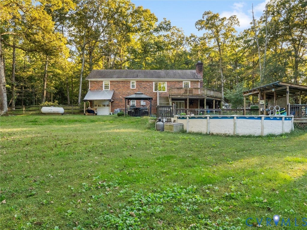 8251 Old Roxbury Road, Quinton, VA 23141 Two-story brick exterior featuring a multi-level wood deck, an above-ground pool with surrounding decking, and mature perimeter trees