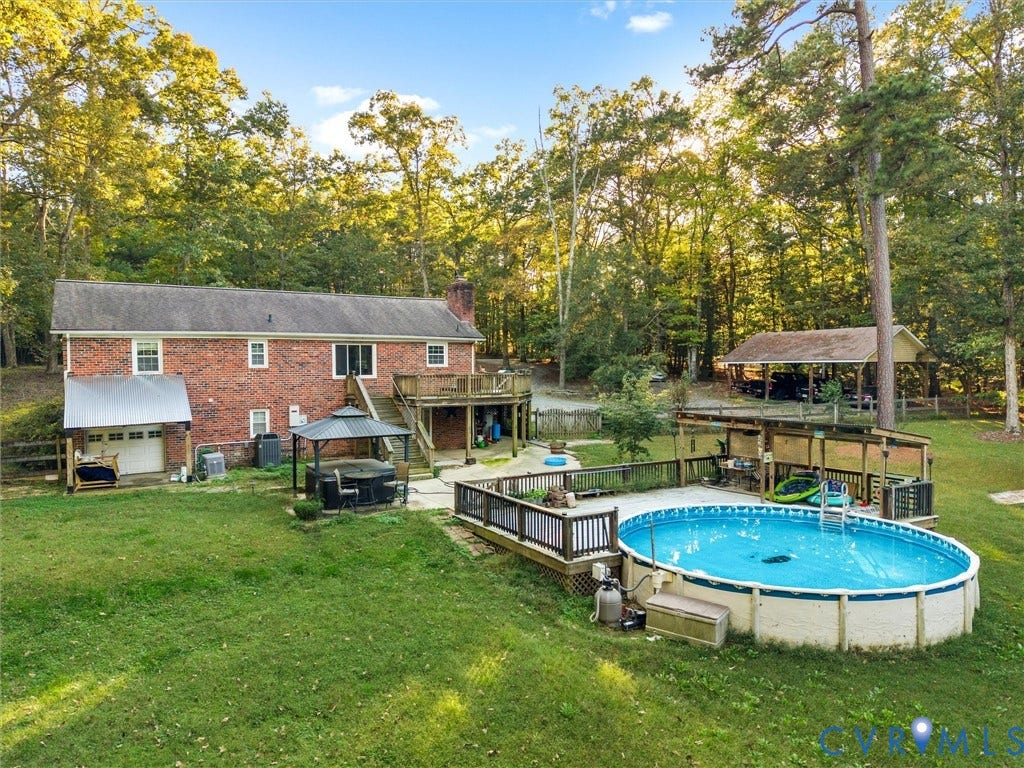 8251 Old Roxbury Road, Quinton, VA 23141 Brick exterior, multi-level wood deck, detached carport, and above-ground pool with surrounding wooden decking