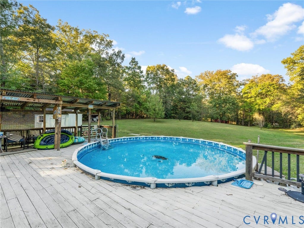 8251 Old Roxbury Road, Quinton, VA 23141 Outdoor space featuring a circular above-ground pool, expansive wood deck, and covered pergola with a metal roof