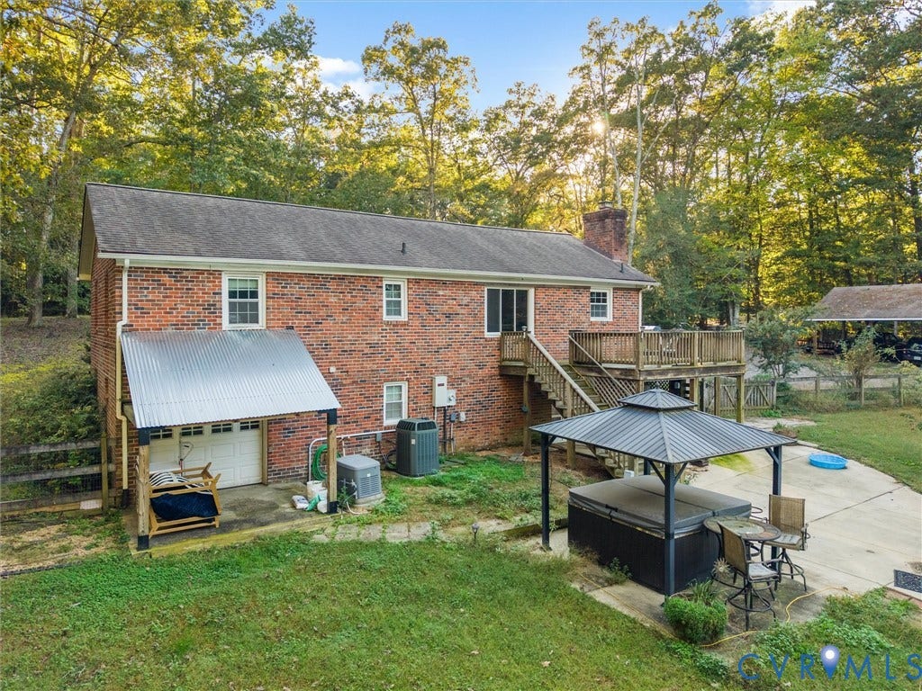 8251 Old Roxbury Road, Quinton, VA 23141 Brick exterior home featuring a raised wooden deck, corrugated metal-roofed lower patio, concrete hardscaping, and an outdoor permanent gazebo structure