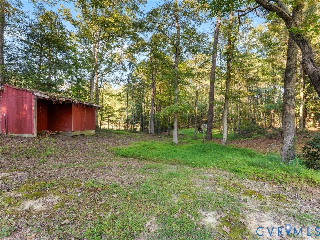 8251 Old Roxbury Road, Quinton, VA 23141 Expansive wooded lot featuring mature trees, natural terrain, and an existing red metal storage structure