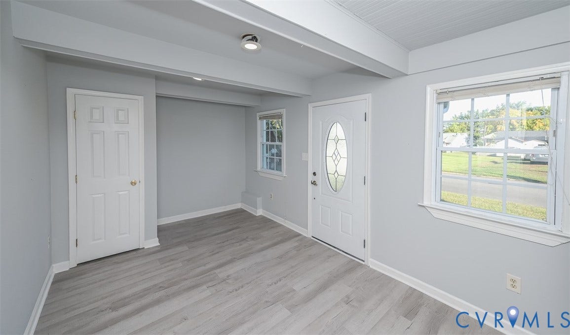 Light gray walls, wood-finish flooring, white paneled doors, recessed lighting, and a front entry door with an oval leaded glass insert