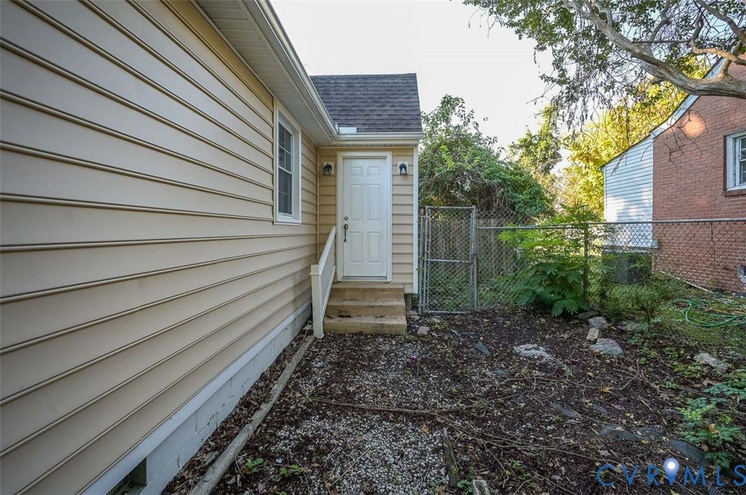 Exterior featuring beige horizontal siding, white trim, and a private side entrance with concrete steps