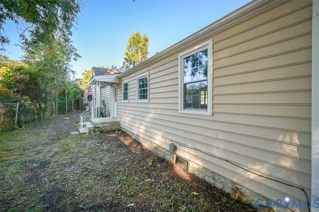 Light-colored horizontal siding and white trim windows on the exterior