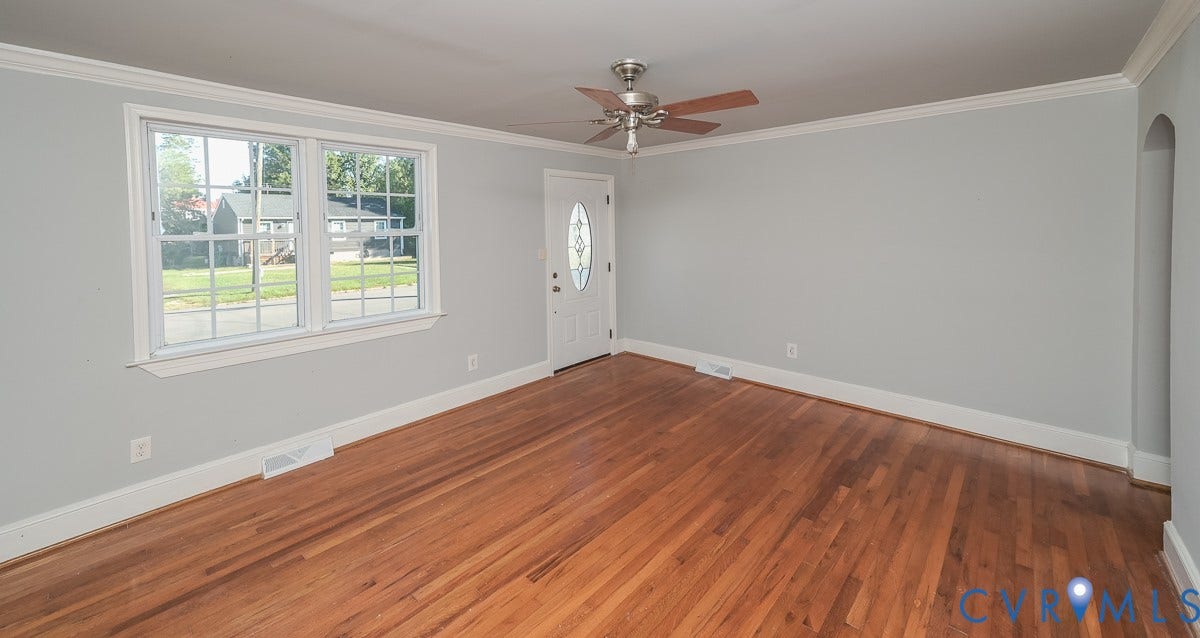 Hardwood flooring, white trim, crown molding, double-pane window, and an arched entry