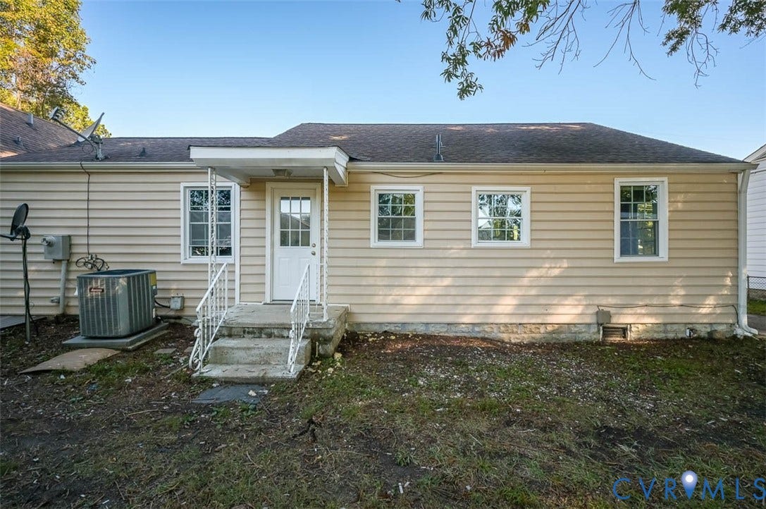 Rear exterior featuring horizontal siding, multiple pane windows, a covered entry, and concrete steps with metal railings