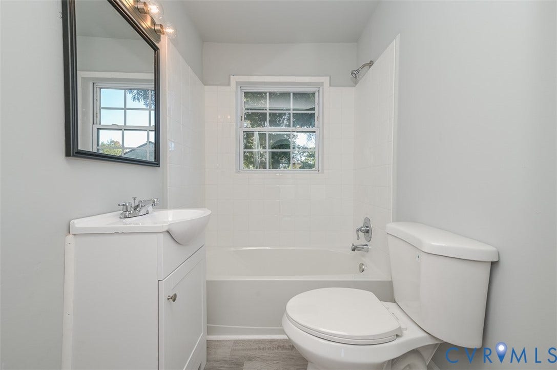 White vanity with an integrated sink, polished chrome faucet, and rectangular framed mirror with attached lighting