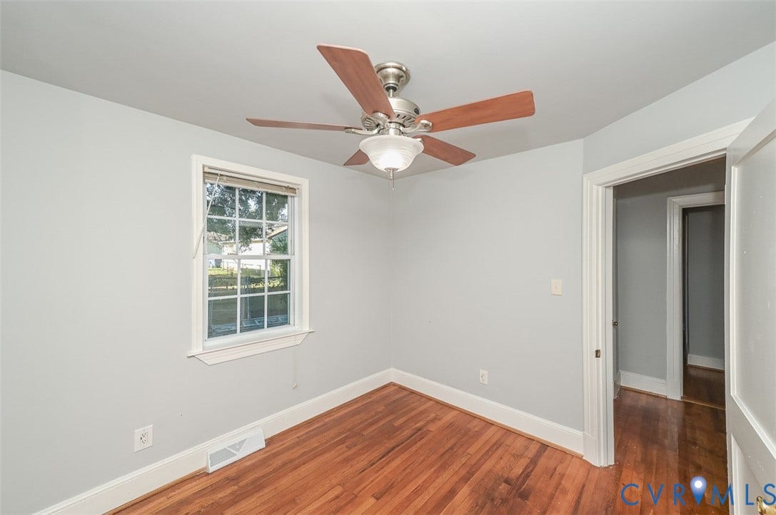 Wood-finish flooring, light grey wall paint, and a ceiling fan with light fixture