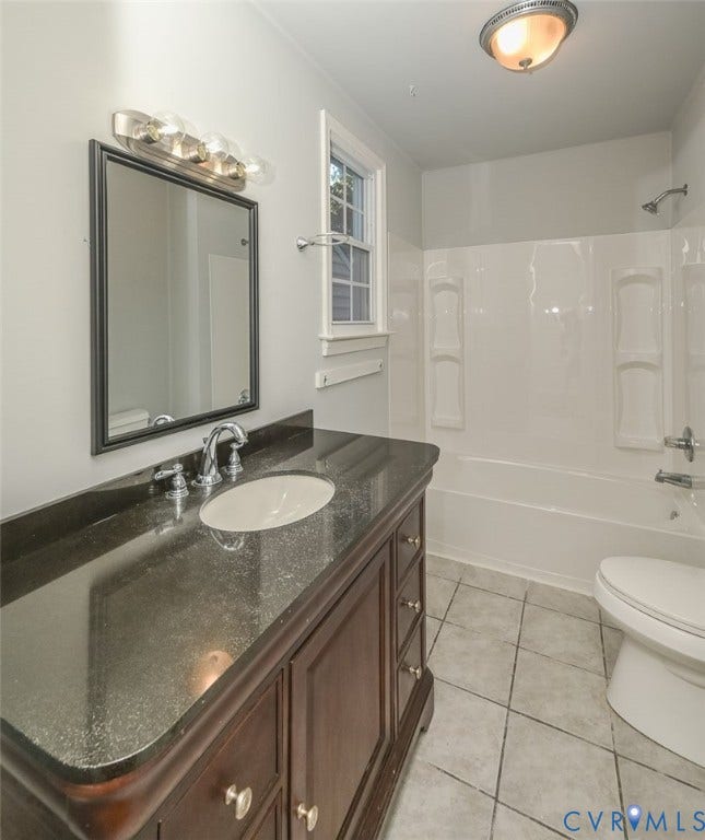 Vanity with a dark countertop, an oval undermount sink, and a chrome faucet