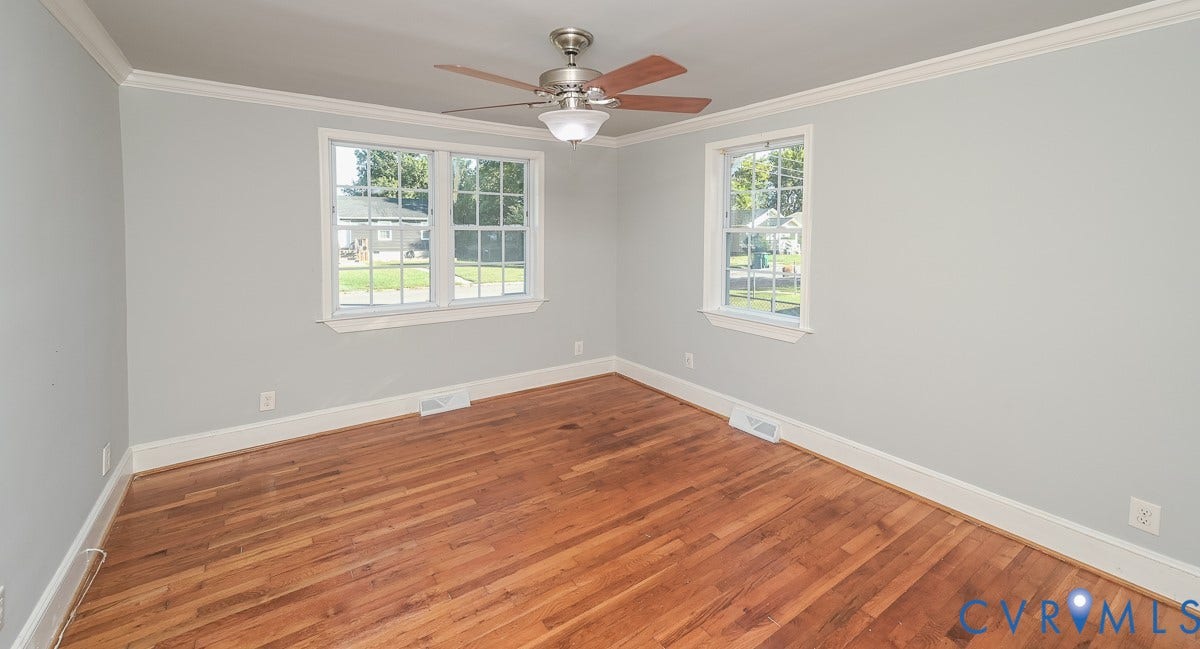 Hardwood flooring, light gray wall finishes, white window trim, and a ceiling fan with integrated lighting