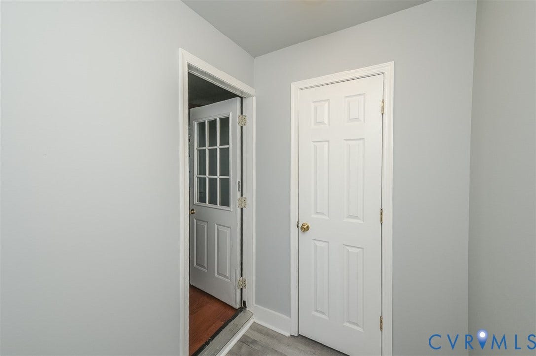 Light gray wall finish with contrasting white trim, featuring a six-panel door with a brass-finish knob